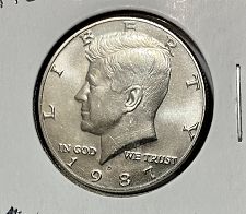 1987 Kennedy half dollar off-center strike error showing design shifted off-center with blank planchet visible